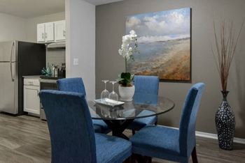 A dining room with a glass table and blue chairs.